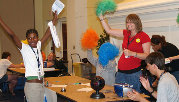A delegate from the 2009 Kansas YLF celebrates visiting the accommodations table during the Real Life Affair, while volunteers celebrate with her.