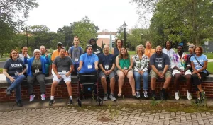 19 people sit on or near a brick wall in Connecticut