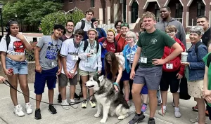 18 delegates stand for a picture with a dog in the middle